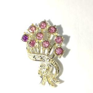 Gold colored brooch with purple stones.